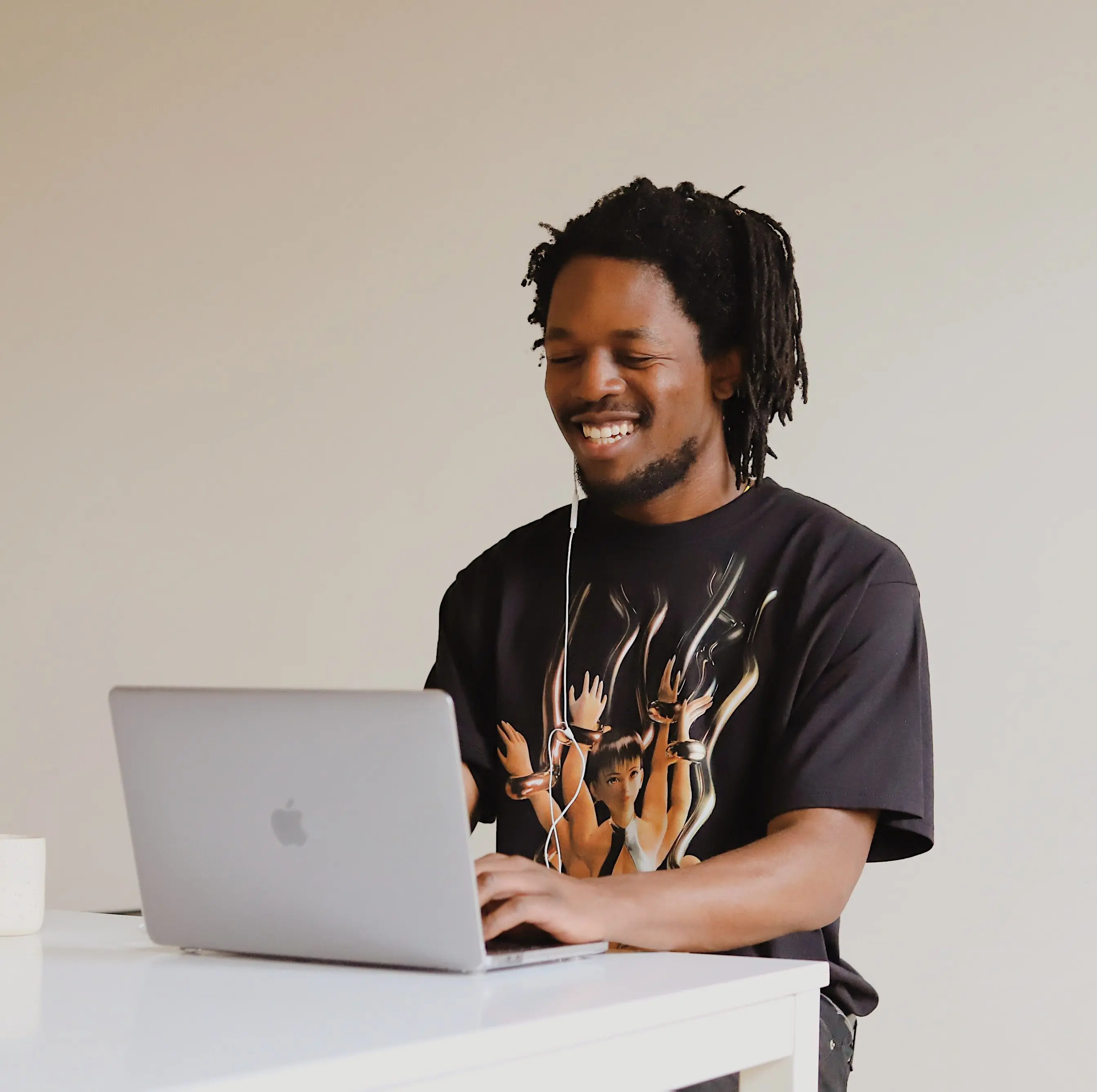 A young man smiles at his laptop during online therapy.